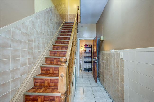 Stairway featuring tile walls, tile patterned flooring, and a wainscoted wall | Image 17