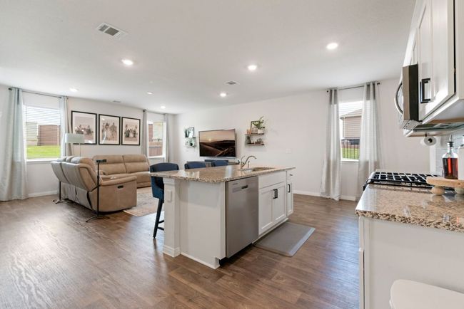 Kitchen with appliances with stainless steel finishes, dark wood finished floors, white cabinetry, open floor plan, and recessed lighting | Image 15