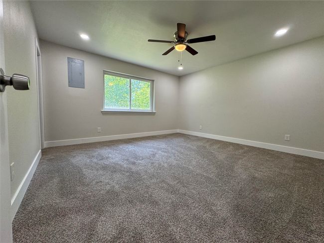 Empty room featuring carpet flooring, baseboards, a ceiling fan, and electric panel | Image 15