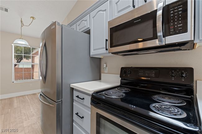 Kitchen featuring stainless steel appliances, light countertops, and hanging light fixtures | Image 11