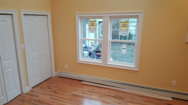 Unfurnished bedroom with baseboard heating and light wood-type flooring | Image 11