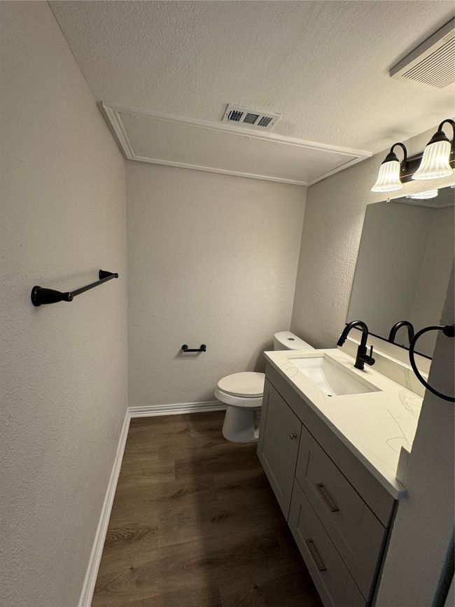 Bathroom with a textured ceiling, vanity, a textured wall, wood finished floors, and toilet | Image 8