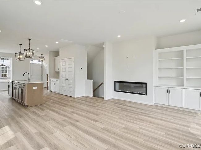 Kitchen with light countertops, light wood-type flooring, recessed lighting, a kitchen island with sink, and decorative light fixtures | Image 13