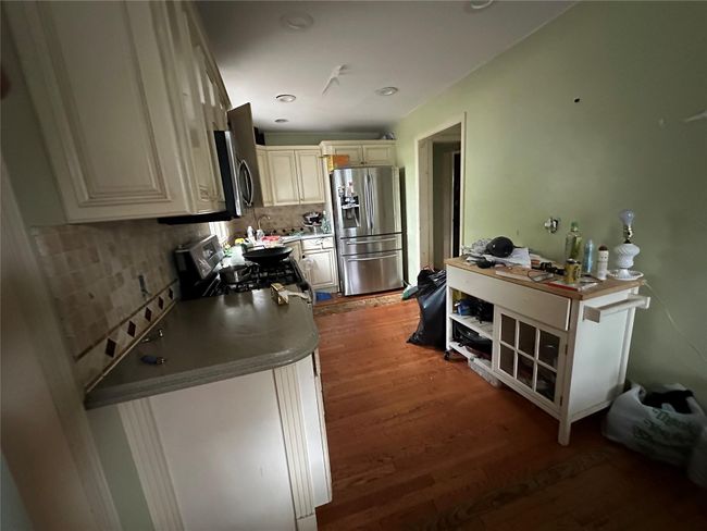 Kitchen with appliances with stainless steel finishes, wood finished floors, backsplash, and cream cabinets | Image 15