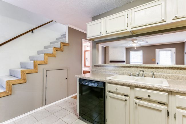 Kitchen featuring black dishwasher, light tile patterned floors, light countertops, a ceiling fan, and ornamental molding | Image 14