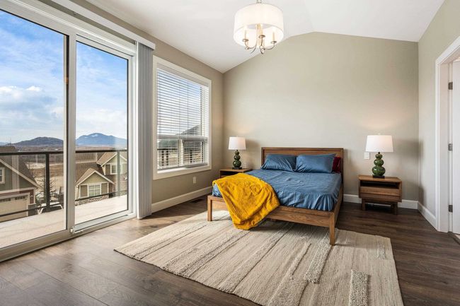 Bedroom with access to exterior, vaulted ceiling, wood finished floors, and a chandelier | Image 21