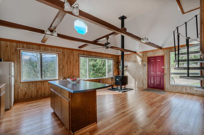 Kitchen featuring wood walls, a wood stove, light hardwood / wood-style floors, and a center island | Image 13