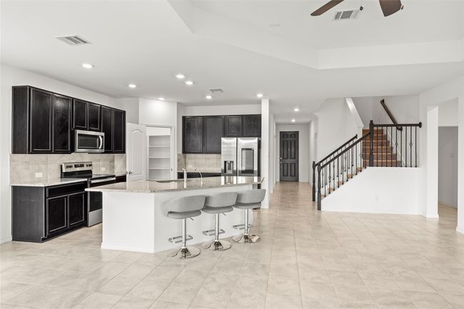 Kitchen with appliances with stainless steel finishes, dark cabinets, a sink, backsplash, and ceiling fan | Image 7