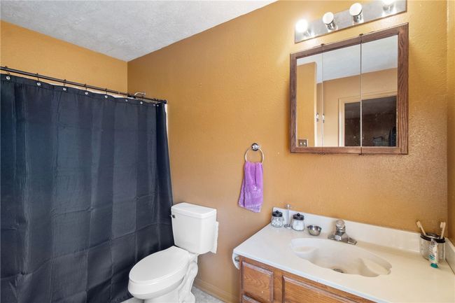 Bathroom with vanity, a textured wall, curtained shower, and a textured ceiling | Image 19