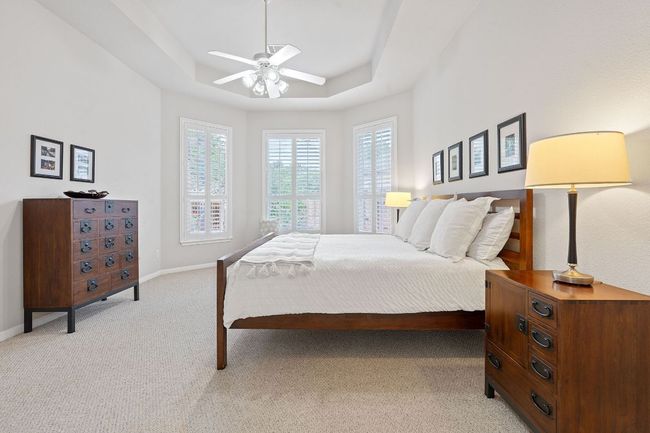Bedroom with multiple windows, a tray ceiling, light carpet, and baseboards | Image 10