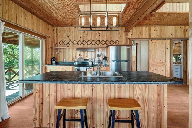 Kitchen featuring dark countertops, wooden ceiling, wood walls, and appliances with stainless steel finishes | Image 16