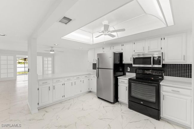 Kitchen with backsplash, appliances with stainless steel finishes, light tile patterned floors, and ceiling fan | Image 20