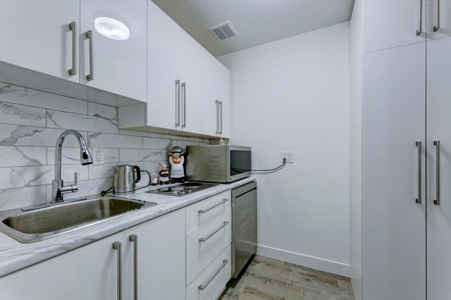 Kitchen with a sink, white cabinets, light wood-style floors, stainless steel appliances, and backsplash | Image 19