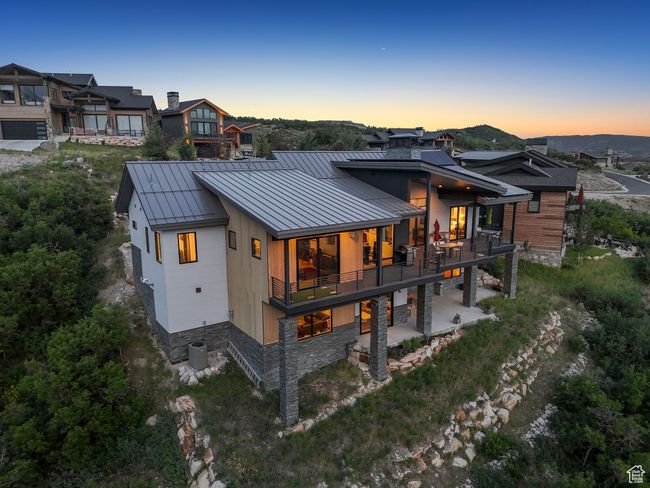 Back of property at dusk with a standing seam roof, a metal roof, a balcony, a patio, and stone siding | Image 81