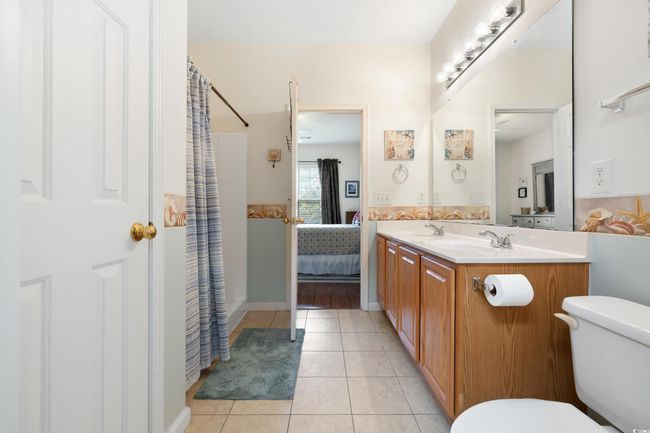 Ensuite bathroom featuring toilet, tile patterned flooring, double vanity, and a shower with shower curtain | Image 22