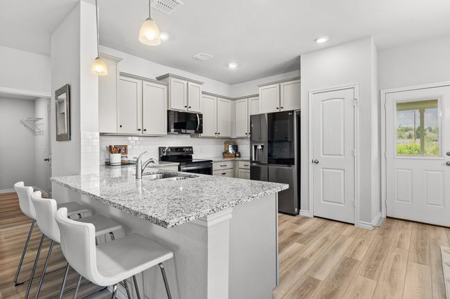 Kitchen with stainless steel appliances, a peninsula, a kitchen bar, light stone countertops, and recessed lighting | Image 21