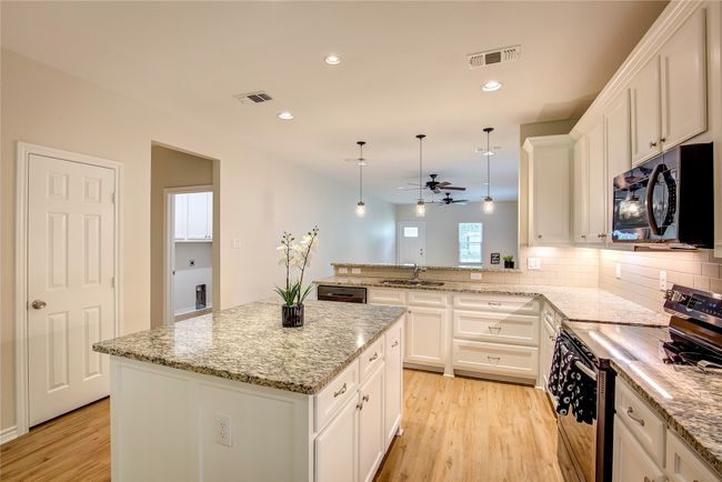 Kitchen featuring electric stove, ceiling fan, light wood-style flooring, white cabinets, and a peninsula | Image 13