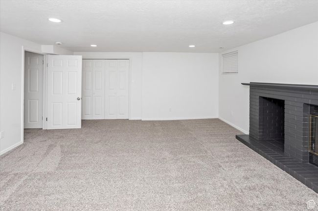 Unfurnished living room with a textured ceiling, a fireplace, baseboards, and carpet | Image 29