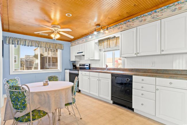 Kitchen featuring stainless steel electric range, wood ceiling, and black dishwasher | Image 12