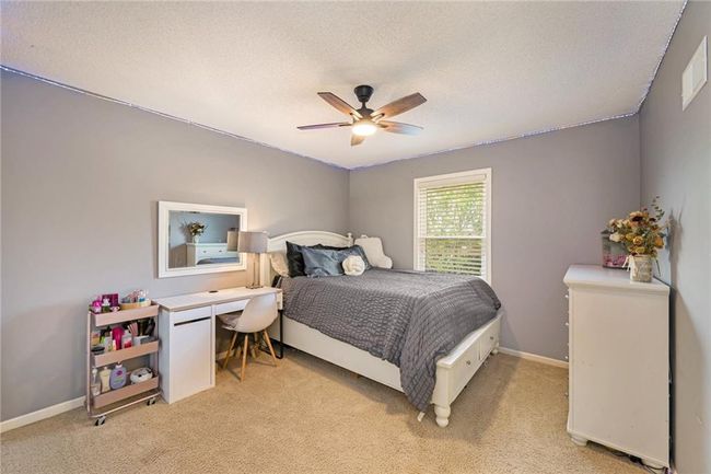 Bedroom with light colored carpet, a textured ceiling, ceiling fan, and baseboards | Image 25