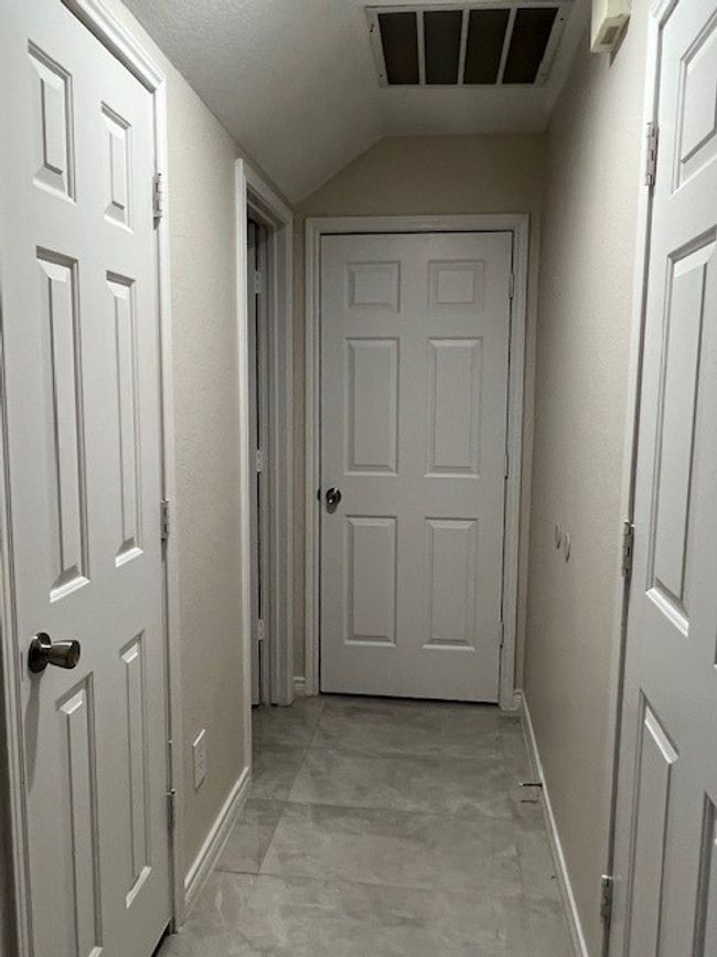 Hallway featuring baseboards and vaulted ceiling | Image 5