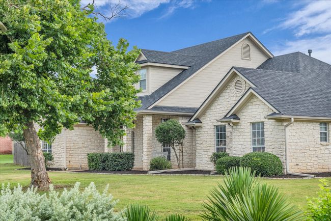 View of front of home featuring stone siding, a front yard, and a shingled roof | Image 4