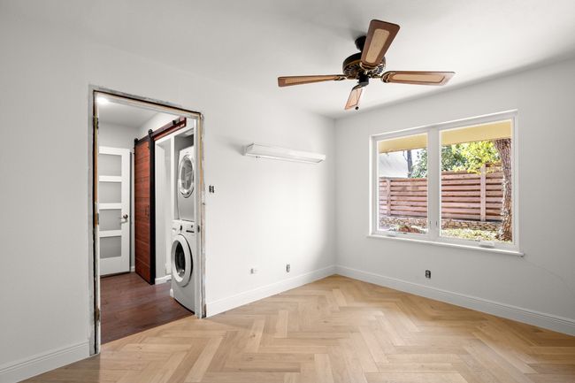 Clothes washing area with ceiling fan, a barn door, laundry area, baseboards, and stacked washing maching and dryer | Image 33