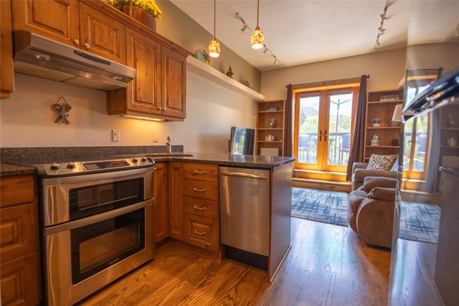 Kitchen with stainless steel appliances, under cabinet range hood, rail lighting, french doors, and brown cabinetry | Image 4