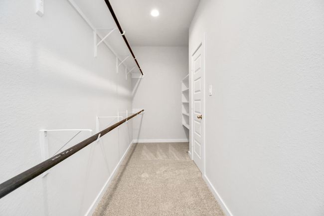 Walk-in closet that epitomizes luxury and practicality. This generously sized space features built-in shelving, offering abundant room for impeccable organization. High ceilings and recessed lighting create a bright and welcoming ambiance. | Image 27