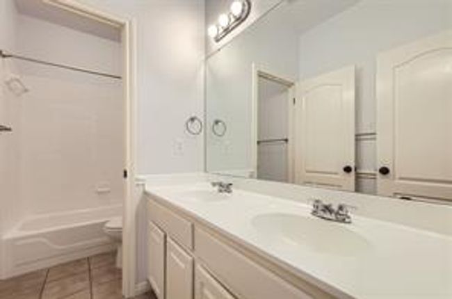 Bathroom featuring double vanity, tile patterned flooring, and shower / bathtub combination | Image 16