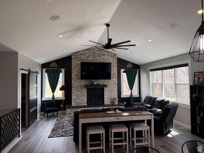 Living area with lofted ceiling, a fireplace, wood finished floors, and a ceiling fan | Image 8