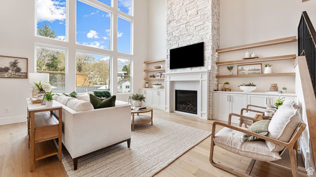 Living area with a fireplace, light wood-style floors, and a high ceiling | Image 18