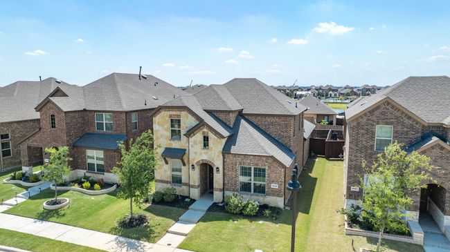 French country home featuring stone siding, a residential view, roof with shingles, and a front yard | Image 31