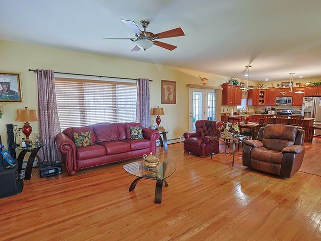 Living area featuring baseboard heating, a ceiling fan, and light wood finished floors | Image 15