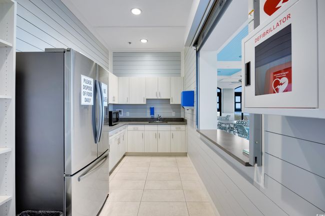 Kitchen with stainless steel fridge with ice dispenser, light tile patterned floors, dark countertops, and recessed lighting | Image 31