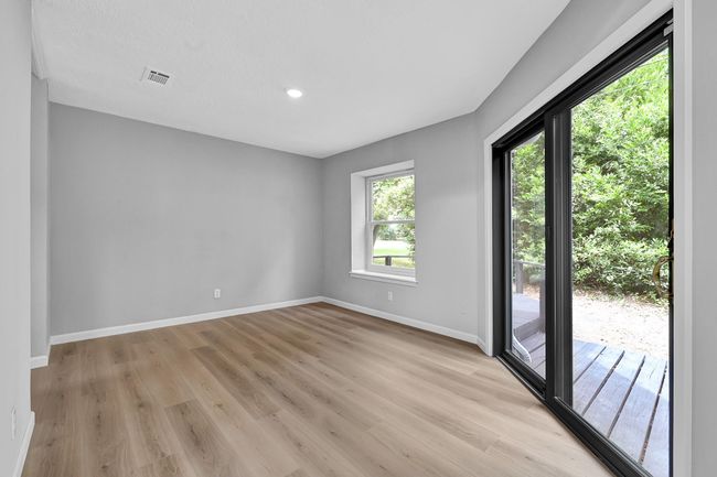 Bright and airy dining room with brand-new flooring, soft neutral walls, and abundant natural light from the large window and sliding glass doors—perfect for indoor-outdoor entertaining with direct access to the deck and backyard. | Image 22