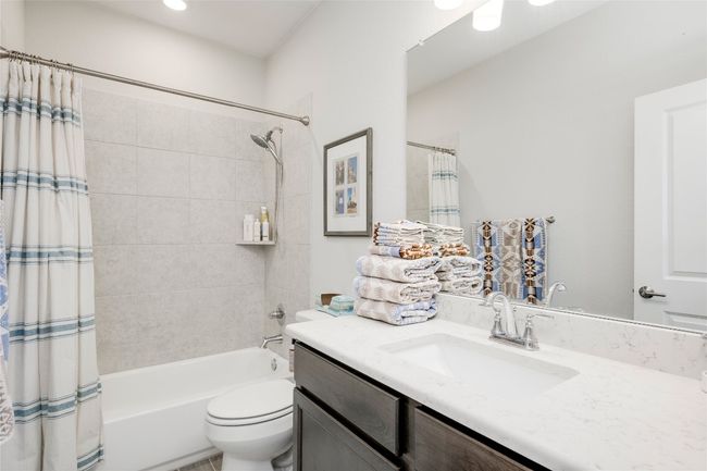 Bathroom with toilet, vanity, and shower / bathtub combination with curtain | Image 23