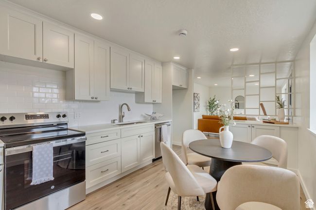 Kitchen featuring white cabinets, appliances with stainless steel finishes, a sink, and light wood-style flooring | Image 10