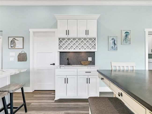 Chic built-in wet bar with quartz countertops, herringbone tile backsplash, and custom wine storage—adds both style and function for effortless entertaining. | Image 11