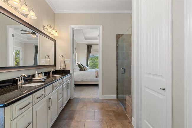 Ensuite bathroom with crown molding, double vanity, a sink, and a stall shower | Image 18