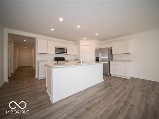 kitchen featuring white cabinetry, light countertops, wood finished floors, and stainless steel appliances | Image 19