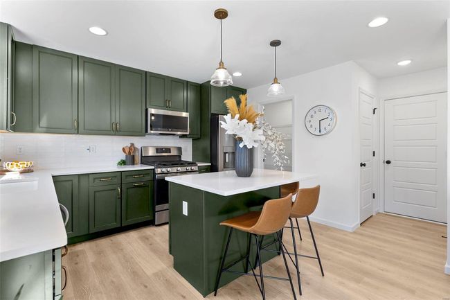Kitchen featuring appliances with stainless steel finishes, pendant lighting, green cabinetry, and light hardwood / wood-style flooring | Image 29