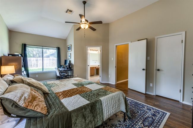 Bedroom with high vaulted ceiling, wood finished floors, baseboards, a desk, and connected bathroom | Image 12