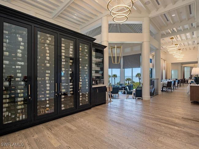 Bay Colony Beach Club Wine room featuring wood finished floors, a chandelier, a bar, beamed ceiling, and a high ceiling | Image 32