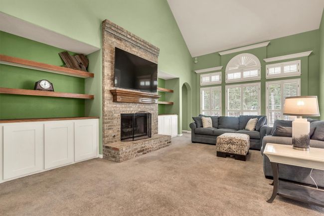 Carpeted living area with arched walkways, a brick fireplace, high vaulted ceiling, and built in features | Image 15