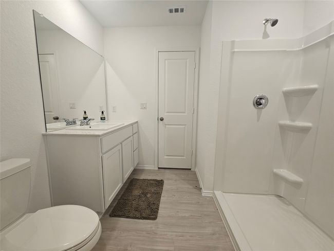 Full bathroom with visible vents, walk in shower, toilet, wood finished floors, and vanity | Image 17
