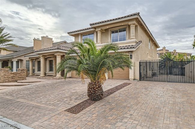Mediterranean / spanish-style house with decorative driveway, stucco siding, a tile roof, and a gate | Image 51