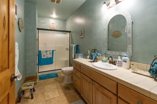 Bathroom with toilet, vanity, a shower stall, and tile patterned flooring | Image 22