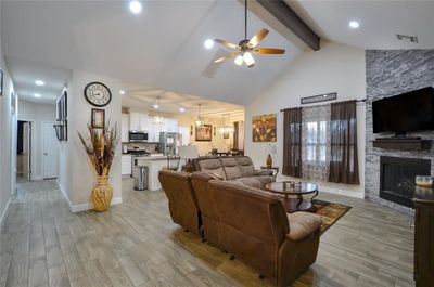 Living room featuring a fireplace, light hardwood / wood-style flooring, beam ceiling, and ceiling fan | Image 3