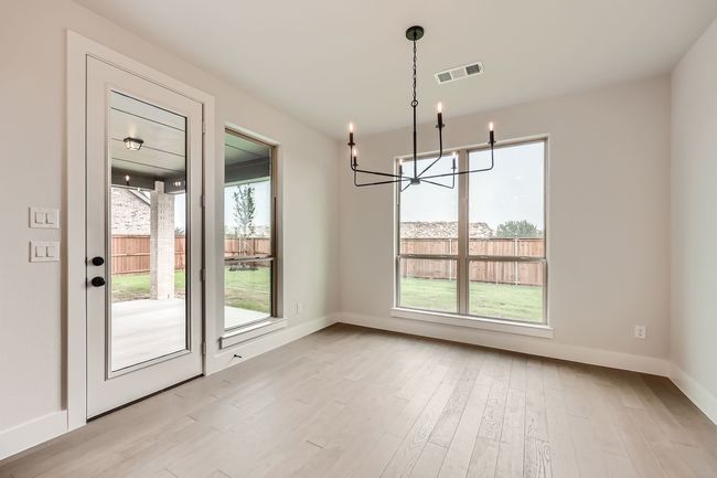Unfurnished dining area featuring a wealth of natural light, visible vents, light wood-type flooring, and a chandelier | Image 8